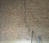 Extensive cracking in a brick wall with render removed